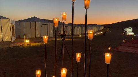 candlelit walkways among small tents in the desert at sunset